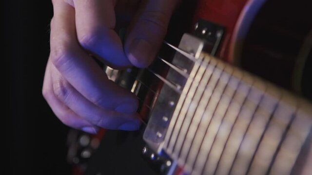 Playing guitar arp chord notes. Musician plays the guitar during a live performance. right hand playing guitar in a bluish lightning. guitar player at a concert rocking audience. just a guitarist
