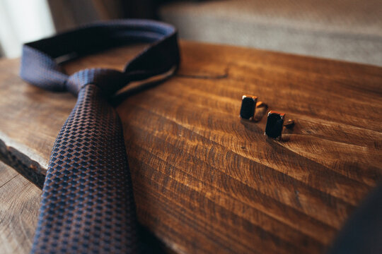 men's tie and cufflinks on a wooden table. close-up high quality photo
