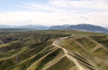Naklejka premium Mountain peaks and grassland are under white clouds.