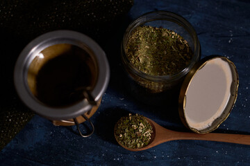 Still life of yerba mate. Glass jar, Calabash and bombilla with yerba mate. Dark food concept.