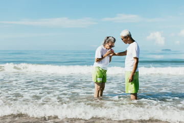 Senior wife having shortness of breath from asthma while strolling along the beach with her husband. Using a nebulizer and inhaler. Older man take care and support wife, Health problem and insurance.