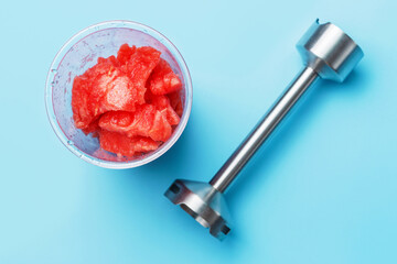 Immersion blender on blue background close-up, top view.