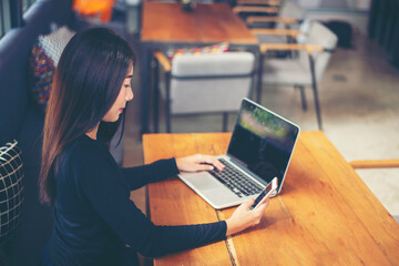 Happy freelance woman is relaxing on comfortable couch and using laptop at home.communicates on Internet with customer.