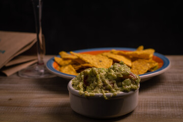 wooden table with wine nachos and guacamole in selective focus