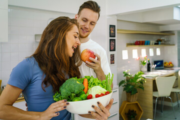 caucasian couple preparing salad for dinner together in kitchen