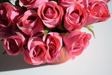 Bright pink artificial flowers in a vase on a white table background