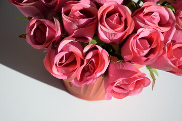 Bright pink artificial flowers in a vase on a white table background