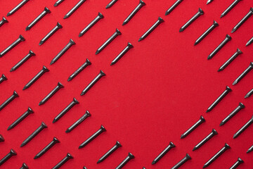 Black steel nails, arranged horizontally, leaving a space in the shape of a rhombus or horizontal...