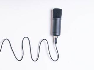 A modern condenser microphone with a wire on a white background.