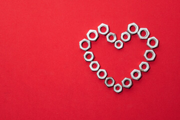 Heart made of steel nuts on red background, concept of love, peace and kindness, leaving space for...