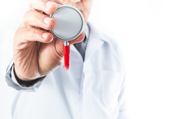 Selective focus of a hand holding a stethoscope, with a doctor out of focus whose face is not recognized