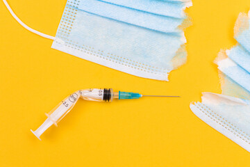 Anti Vaccine Movement and Anti Mask Concept - Broken Medical Syringe and Torn Medical Face Mask...
