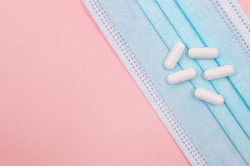 White Pills or Tablets on Medical Face Mask, Lying on Pink Background. Pharmaceutical Industry and Medicinal Products