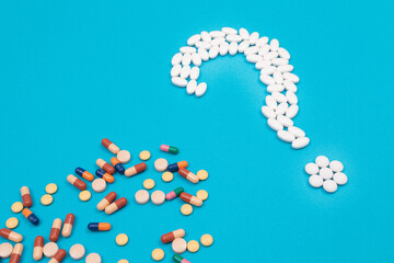 Question Mark Made from White Pills and Tablets with Colored Capsules, Lying on Blue Background. Global Pharmaceutical Industry and Medicinal Products