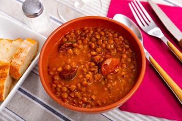 Traditional Spanish stewed lentils with meat, spicy chorizo sausages and vegetables in gravy served...