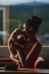 mujer morena sentada besando a su mascota con la lengua