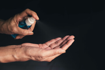 Hand of female that spraying apply alcohol anti virus covid-19 cleaning hand protect life on dark background.