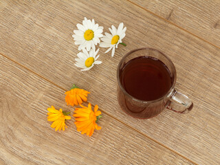 Glass cup of tea with white chamomile flowers