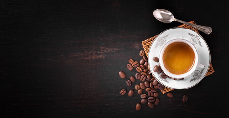 Vintage espresso cup with silver spoon and coffee beans on old dark wooden table, top view, space...