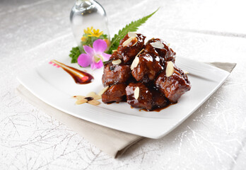 Stir fried dark plum sweet and coffee sauce pork spare ribs meat with almond in white background asian banquet menu