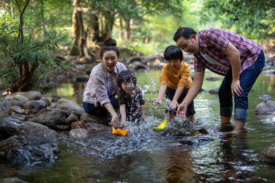 Two Son Playing With Paper Boats At River ,Asian Family Happy