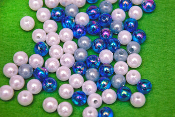 Beads spread on green background. Background or texture of beads. Close up.