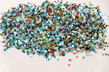 colorful beads scattered on a white background, beads for beadwork, beads for needlework, close-up