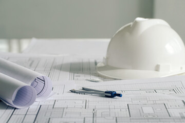 white hard safety wear helmet hat placed on blueprint at construction site-building. helmet for...