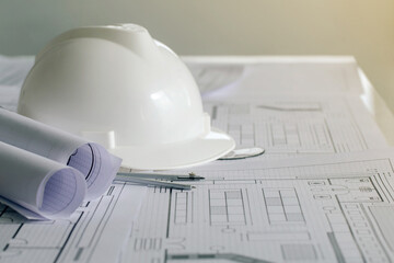 white hard safety wear helmet hat placed on blueprint at construction site-building. helmet for...