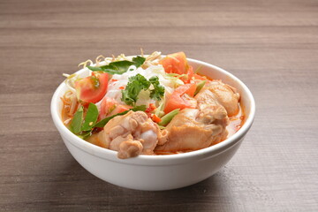 braised cook chicken drumstick meat with red spicy curry soup and vermicelli noodle in wood background asian halal menu