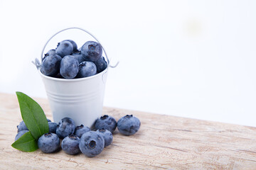 
Blueberries in a bucket on a wooden table.
