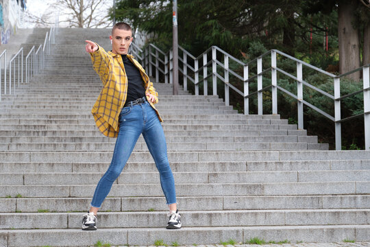 Young non binary person dancing and listening music in the street. Make up androgynous person.