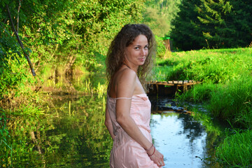 A young beautiful girl is walking along the river in the forest.Unity with nature