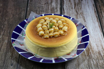 Cheese cake topping with macadamia nuts dressing with caramel serving on the plate. Famous traditional birthday cake in Asia.  