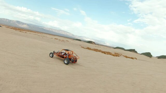 Orange Dune Buggy Driving in the Desert Sand Dunes