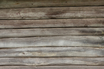 The surface of an old wooden wall made of boards darkened by time and weather. Traditional Russian construction of houses made of wood.