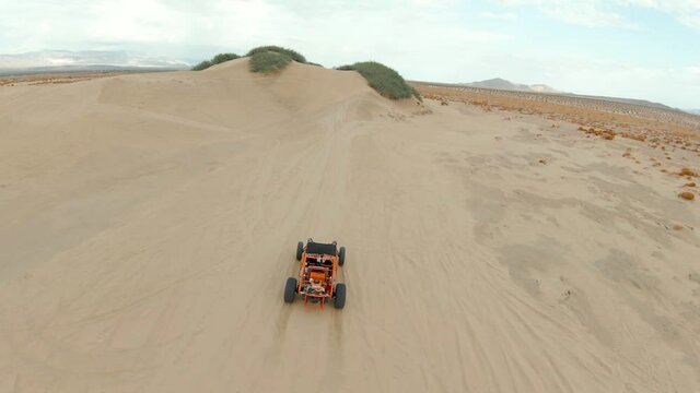 Orange Dune Buggy Driving in the Desert Sand Dunes