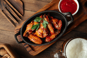 Cast iron plate of fried chicken wings in teriyaki sauce