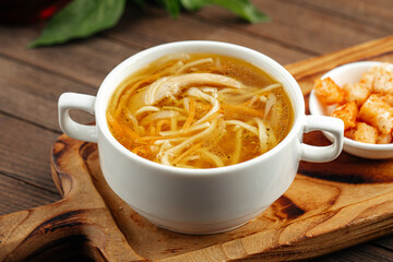 Chicken noodle soup with croutons on wooden background