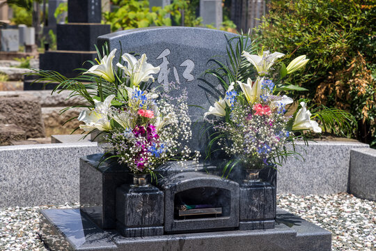 墓参りで墓に満開の花と線香を供える