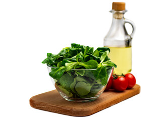 Mung bean salad leaves, corn salad in a glass bowl on a wooden board, cherry tomato, isolate. Fresh blend of green washed leaves and vegetable oil (Valerianella locusta). Diet and healthy food concept