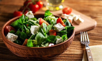 Salad from lettuce leaves mung bean, cheese, cherry tomatoes, in a ceramic bowl on a wooden board close-up (Valerianella locusta). Diet and healthy eating, vegetarianism. Soft focus. keto diet 