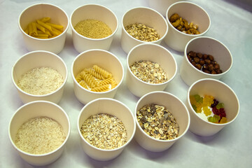 Eating for a sample. Cups with pasta, nuts, cereals, oat flakes, rice, marmalade for shop attendees
