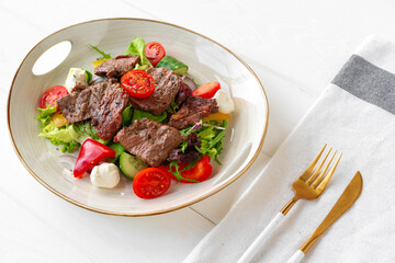 Fillet of beef with vegetable salad on wooden table