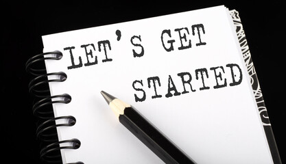 Obraz premium LET'S GET STARTED written text in small notebook on a black background