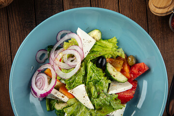 Plate of greek salad with fresh vegetables on wooden decorated background