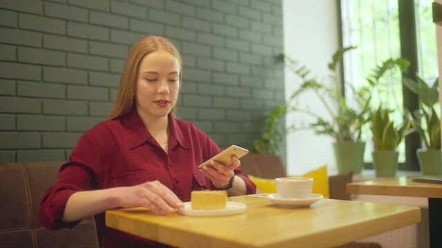 Waiter serving cake to female customer, woman taking food pictures on smartphone