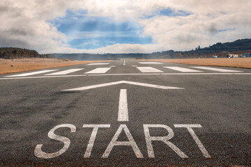 White arrow on a small asphalt air plane runway. Cloudy sky with