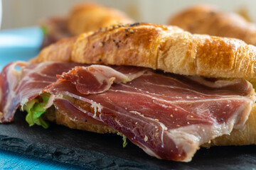 Croissant stuffed with Serrano ham, with lettuce and sesame and poppy seeds.