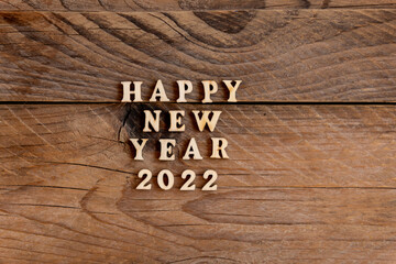 Happy New Year 2022. Quote made from wooden letters and numbers 2022 on wooden background. Creative concept for new year greeting card